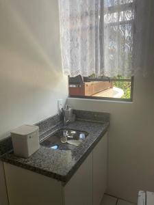 eine Küchentheke mit einem Waschbecken und einem Fenster in der Unterkunft Kitnet Beira Rio in Alfredo Wagner