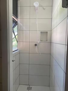 a white tiled shower with a shower head at Kitnet Beira Rio in Alfredo Wagner