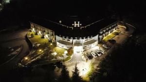 un gran edificio con coches aparcados delante de él por la noche en Hotel Theotokos, en Viggiano