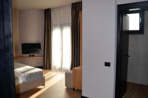 een hotelkamer met een bed en een televisie bij N'Peze Hotel in Tirana