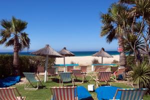 Bungalows Tangana في تريفة: مجموعة من الكراسي والمظلات على الشاطئ