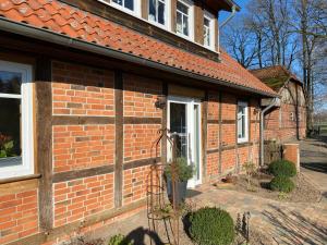 a red brick house with a white door at Ferienwohnung Hof Falke in Suderbruch
