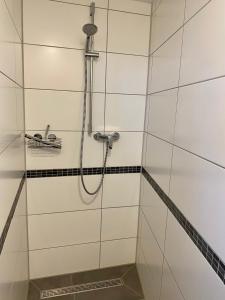 a shower in a bathroom with white tiles at Ferienwohnung Hof Falke in Suderbruch +15 photos