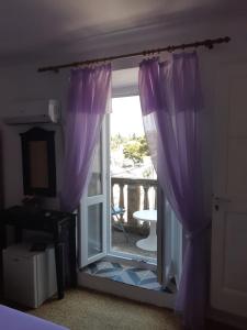 eine Glasschiebetür mit lila Vorhängen in einem Zimmer in der Unterkunft Rooms Milena in Lopud Island
