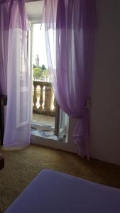 um quarto com uma janela com cortinas roxas em Rooms Milena em Lopud