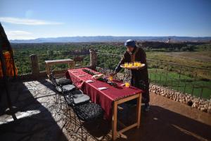 un uomo che tiene un piatto di cibo sopra un tavolo di Kasbah Itran a El Kelaa des Mgouna