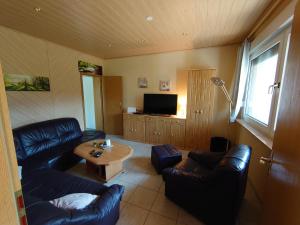 ein Wohnzimmer mit Sofas, einem Tisch und einem TV in der Unterkunft waldhaus lioba in Zichtau