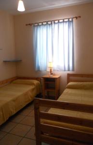 a room with two beds and a window with a lamp at Islantilla Casa Adosada 700 metros de la playa in Islantilla