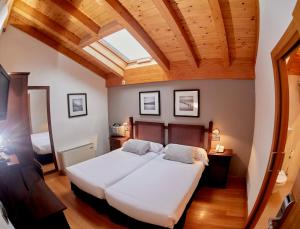 a bedroom with a large white bed with a skylight at Hotel Casa Azcona in Zizur Mayor