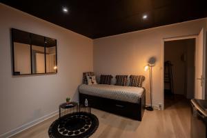 Schlafzimmer mit einem Bett und einem Wandspiegel in der Unterkunft La Suite "Black Hood" in Maubeuge