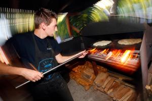 a man is cooking food in a grill at Mobil Home XXL 4 chambres - Camping Le Giessen in Bassemberg
