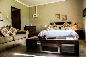 a bedroom with a bed and a couch and a table at Gerald's Gift Guest House in Addo