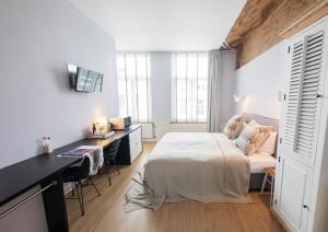 a bedroom with a bed and a desk with a computer at Stadsvilla Hotel Mozaic Den Haag in The Hague