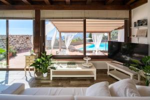 een woonkamer met een witte bank en een tv bij Poolhaus Sicilysun Holidays Giulia in Letojanni