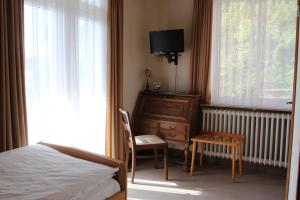 Schlafzimmer mit einem Bett, einem Schreibtisch und einem Fenster in der Unterkunft Hotel Restaurant Siegblick in Siegburg