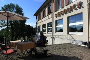 Ein Mann, der vor einem Gebäude an einem Tisch sitzt. in der Unterkunft Hotel Restaurant Siegblick in Siegburg