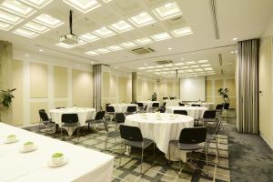una sala conferenze con tavoli e sedie bianchi di Morrissey Hotel Residences a Giacarta