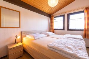 una camera da letto con un letto e due finestre di Ferienwohnpark Immenstaad am Bodensee Satteldachhaus Typ 9 SD 61 a Immenstaad am Bodensee