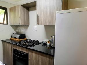a kitchen with a stove and a white refrigerator at Rest-a-While Guest House - Pretoria in Pretoria