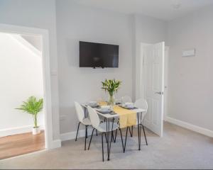 uma sala de jantar branca com uma mesa e cadeiras em The Mila - Ayr Racecourse - Coorie Doon Apartments em Ayr