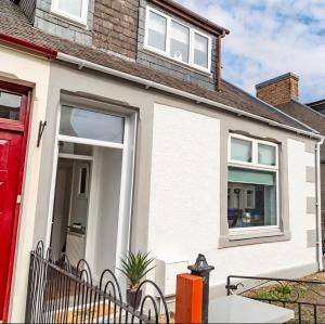 a white house with a red door at The Mila - Ayr Racecourse - Coorie Doon Apartments in Ayr