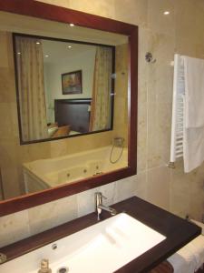 a bathroom with a sink and a mirror and a tub at Hotel Mulhacen in Guadix