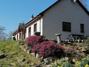 a house on a hill with flowers in front of it at Corrie View in Invergarry