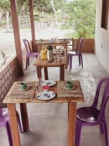 twee houten tafels en stoelen met borden en bekers bij POUSADA DO BETO in Atins