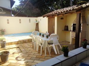 a patio with a table and chairs next to a pool at Casa com Piscina Paraty in Paraty