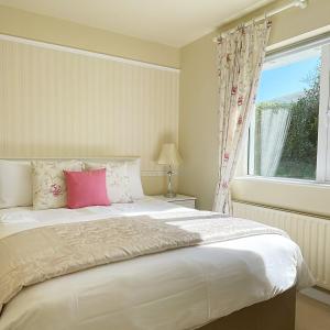 a bedroom with a large bed with a pink pillow at Duinin House B&B in Dingle
