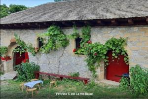 a stone house with a red door and a bench at Rajacke pivnice Country House C`est La Vie in Rajac