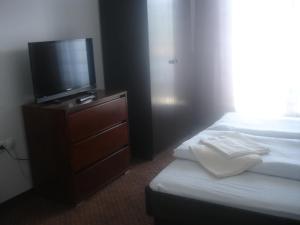 a bedroom with a dresser with a tv and a bed at Tiffany Pension Bled in Bled