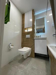 een badkamer met een wit toilet en een wastafel bij “Same as Home apt”M.Zhusupa str. 284/1 in Pavlodar