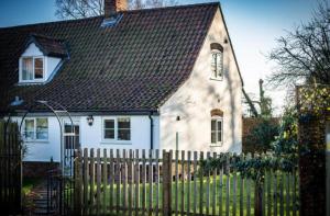 a white house with a fence in front of it at Dreamy Suffolk Country Cottage Escape in Aldeby