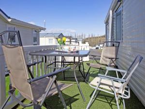 a patio with chairs and a table on a balcony at Hillside Caravan in Dawlish