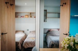 a bedroom with two beds and a door with a mirror at Mobil Home XXL 4 chambres - Camping Le Brabois in Villers-lès-Nancy