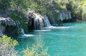 a river with blue water and a waterfall at bellazaira in Ruidera