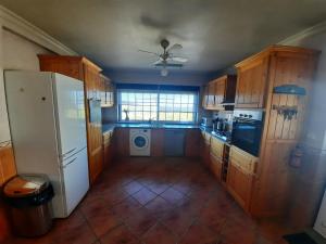 eine Küche mit Holzschränken und einem weißen Kühlschrank in der Unterkunft Casa-Estaro in Anceriz