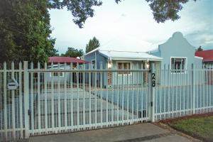 uma cerca branca em frente a uma casa com piscina em A Touch of Grace em Potchefstroom