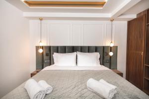 Kantoni Luxury Suites في مدينة كورفو: غرفة نوم بسرير كبير وفوط بيضاء