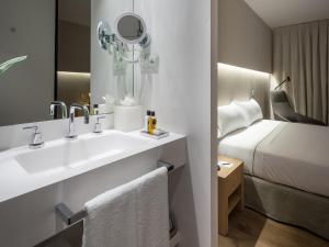 baño con lavabo, cama y espejo en Hotel Sorli Emocions, en Vilassar de Dalt