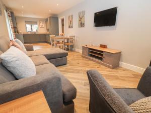 a living room with couches and a flat screen tv at Timadon Cottage in Chester