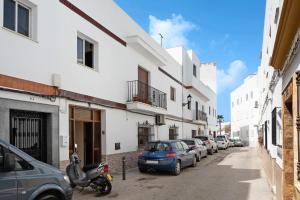 a street with cars parked next to white buildings at Casa La Perla - Solo Familias in Conil de la Frontera