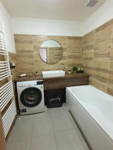 a bathroom with a tub and a sink and a washing machine at Apartmán Frida in Nová Baňa