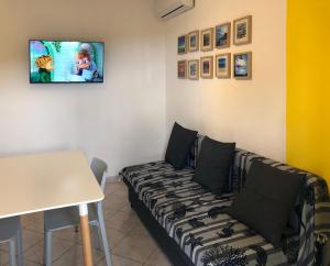 a living room with a couch and a tv on a wall at LuGa Apartments in Campomarino