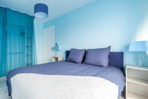 a blue bedroom with a large bed with purple pillows at L'Escale Marine in Dunkerque