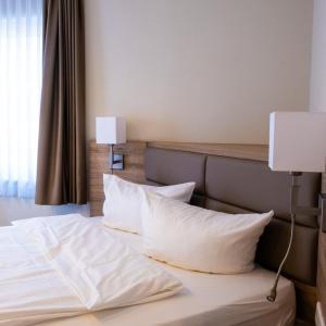 Bett mit weißen Kissen in einem Hotelzimmer in der Unterkunft Akzent Hotel Saltenhof in Hörstel