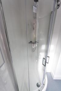 a shower with a glass door next to a toilet at Beamont House in Warrington
