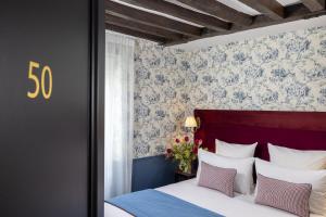 a bedroom with a bed with a red headboard at Hotel Louis II in Paris