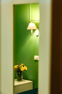 un mur vert avec une lampe et un vase de fleurs dans l'établissement Lydka Domus, à Rome